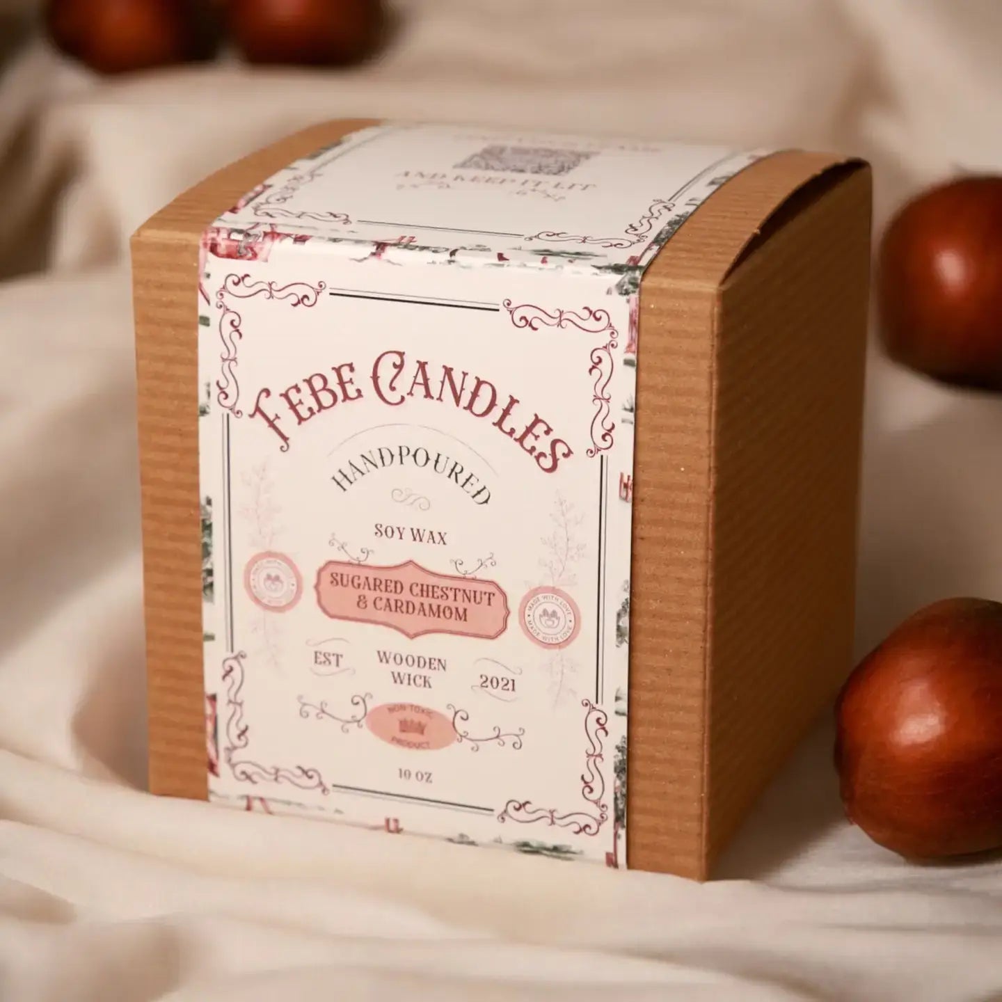 Fabe Candles packaging with decorative design on a soft fabric background