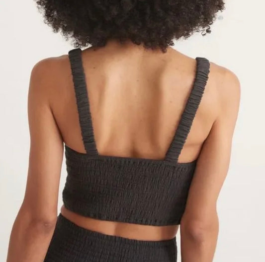 Person wearing a black textured crop top on a plain background