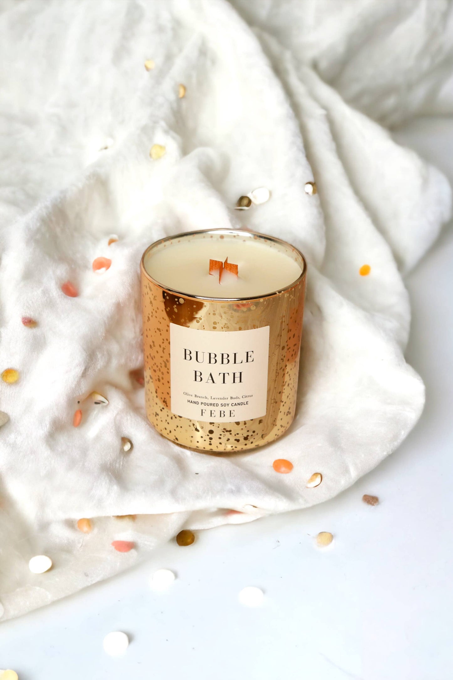 Candle labeled 'Bubble Bath' on a white fabric background