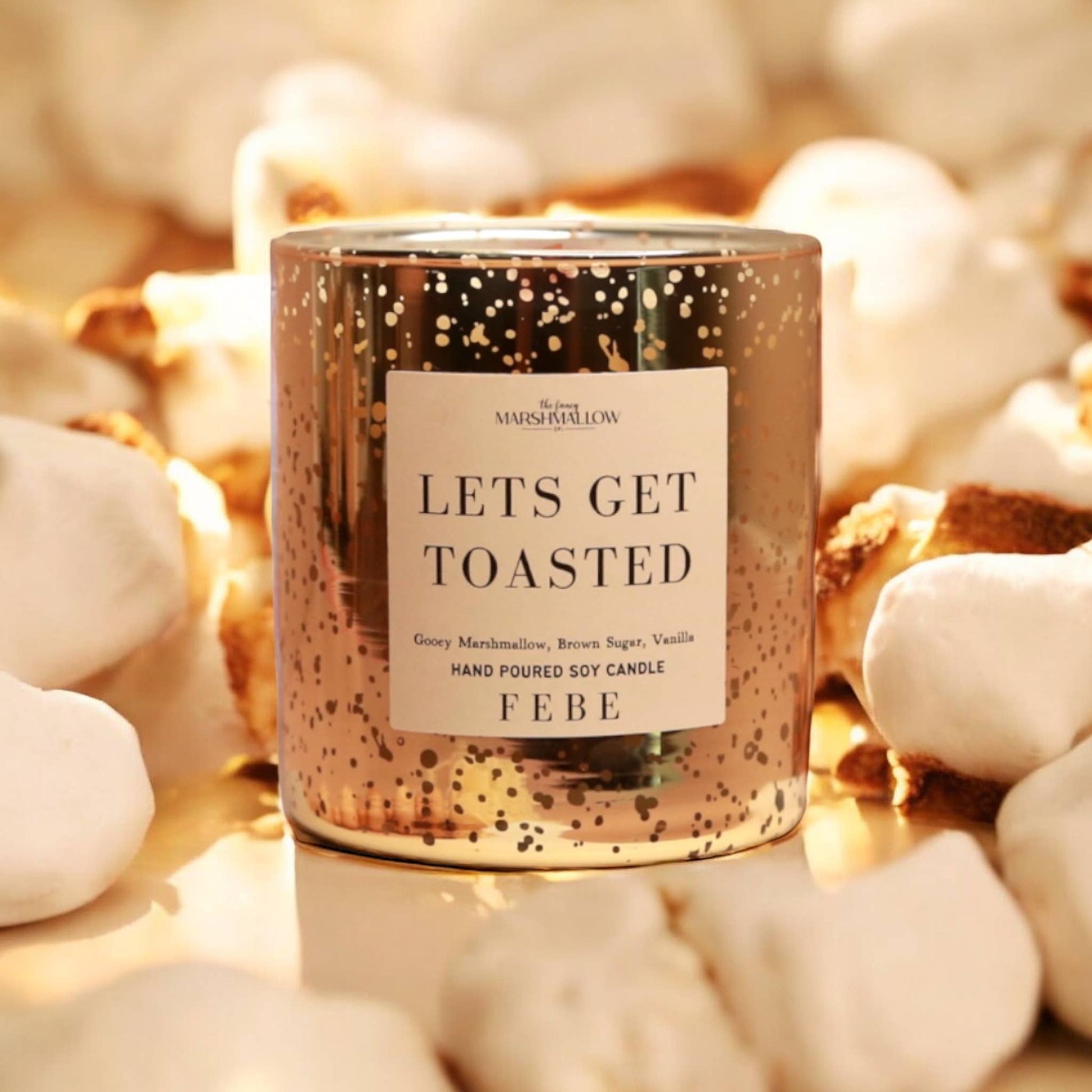 Candle labeled 'Let's Get Toasted' by FEBE on a soft focus background