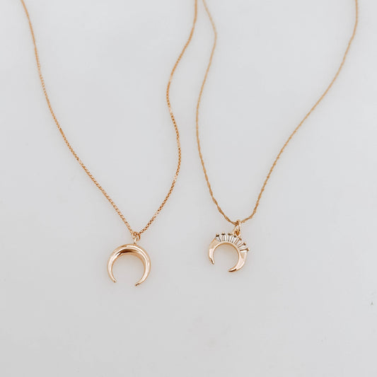 Two gold necklaces with crescent moon pendants on a light gray background