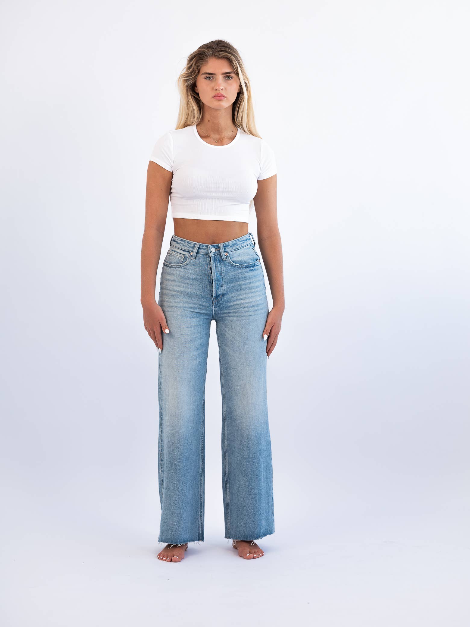 A female model wearing high-rise wide-leg non-stretch denim jeans with a vintage-inspired light wash and scissor-cut hem.