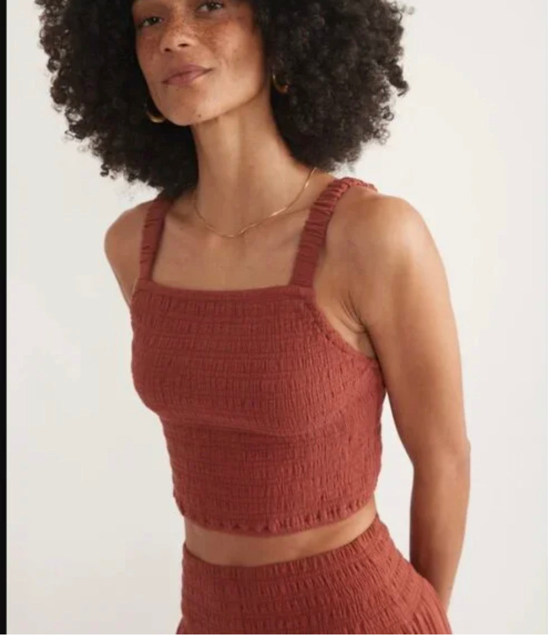 Woman wearing a rust textured top against a white background