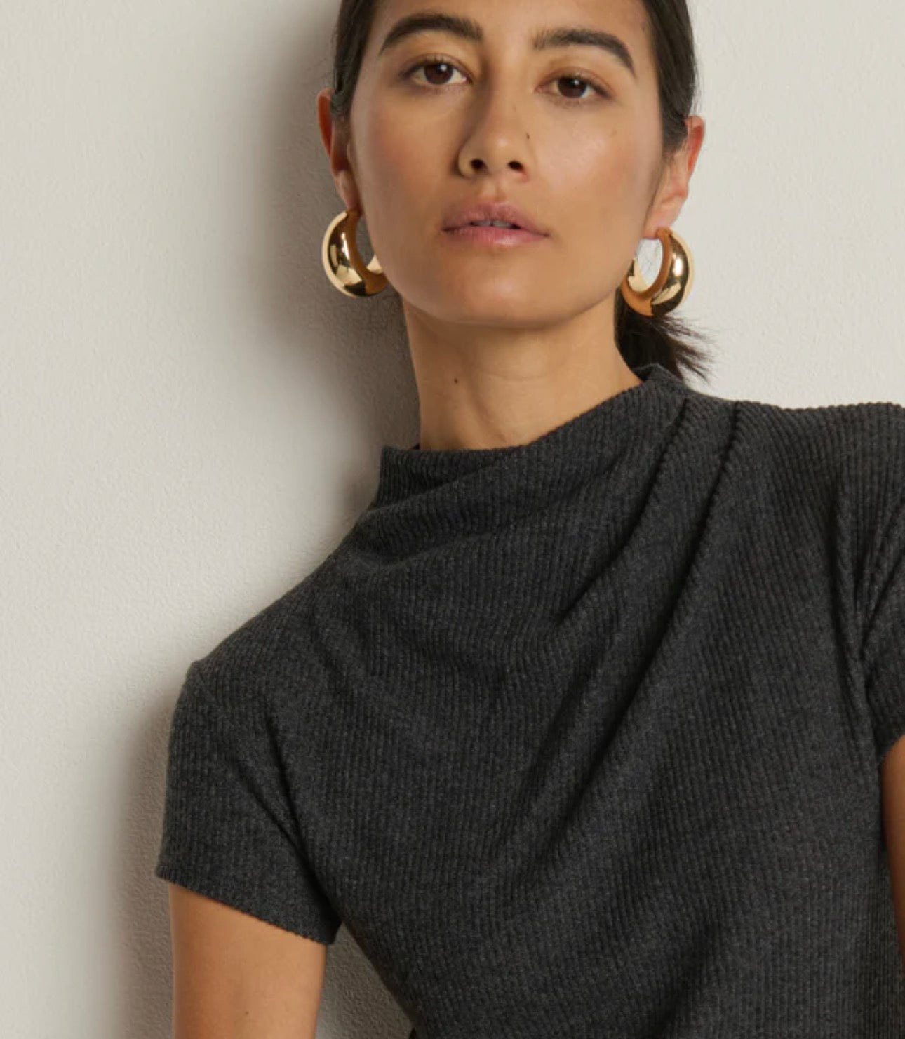 Woman wearing a dark gray turtleneck sweater against a plain background