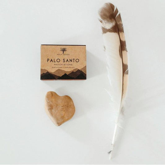 Palo Santo match sticks packaging with a heart-shaped wooden piece and feather on a white background