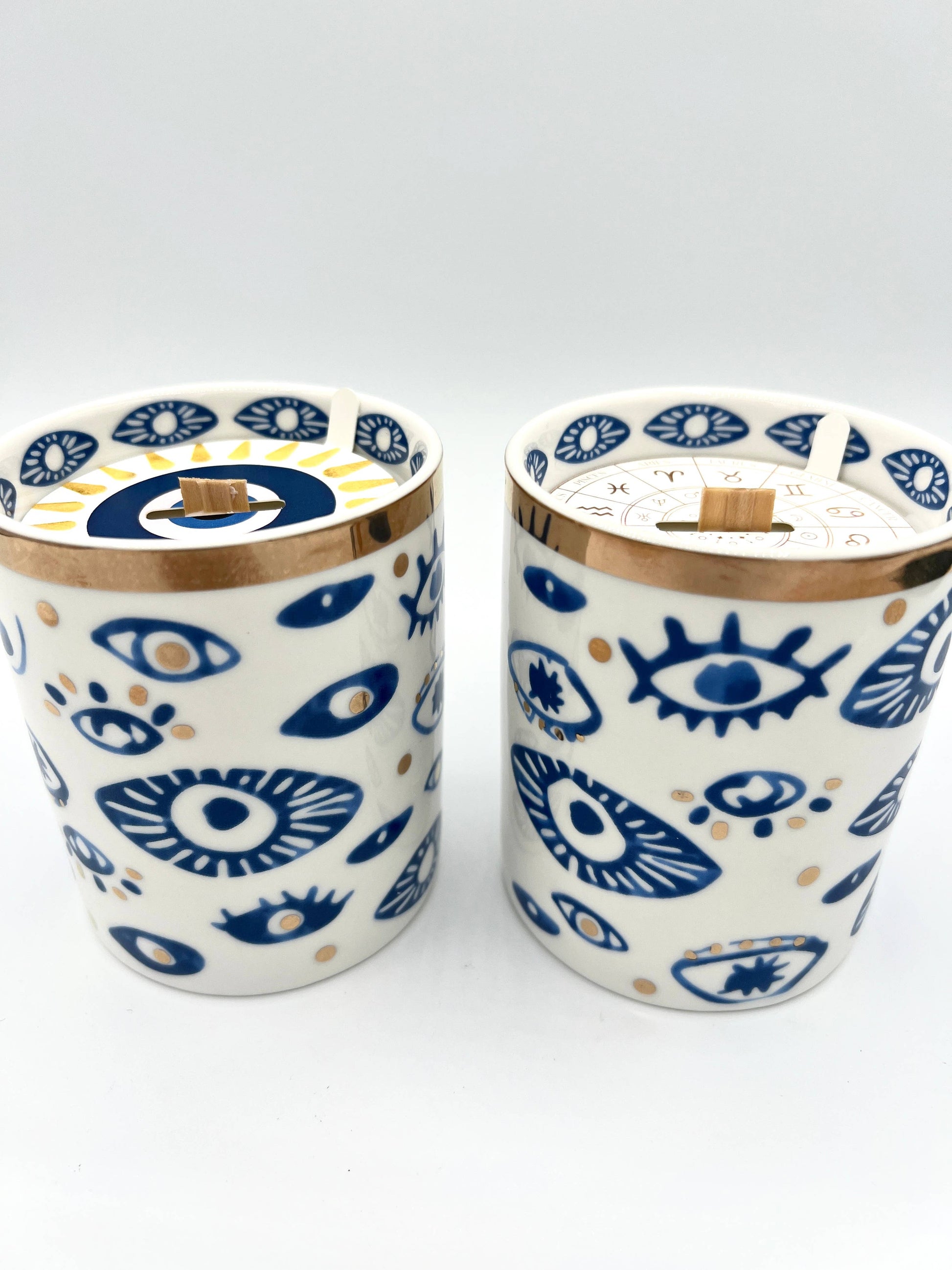 Two ceramic tumblers with eye pattern on a white background