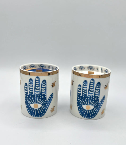 Two ceramic cups with blue hand designs on a white background