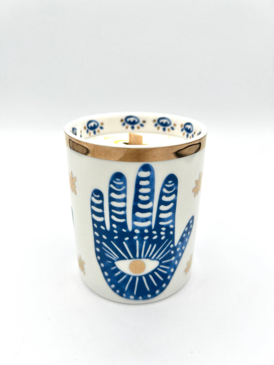 Ceramic candle holder with blue hand design on a white background