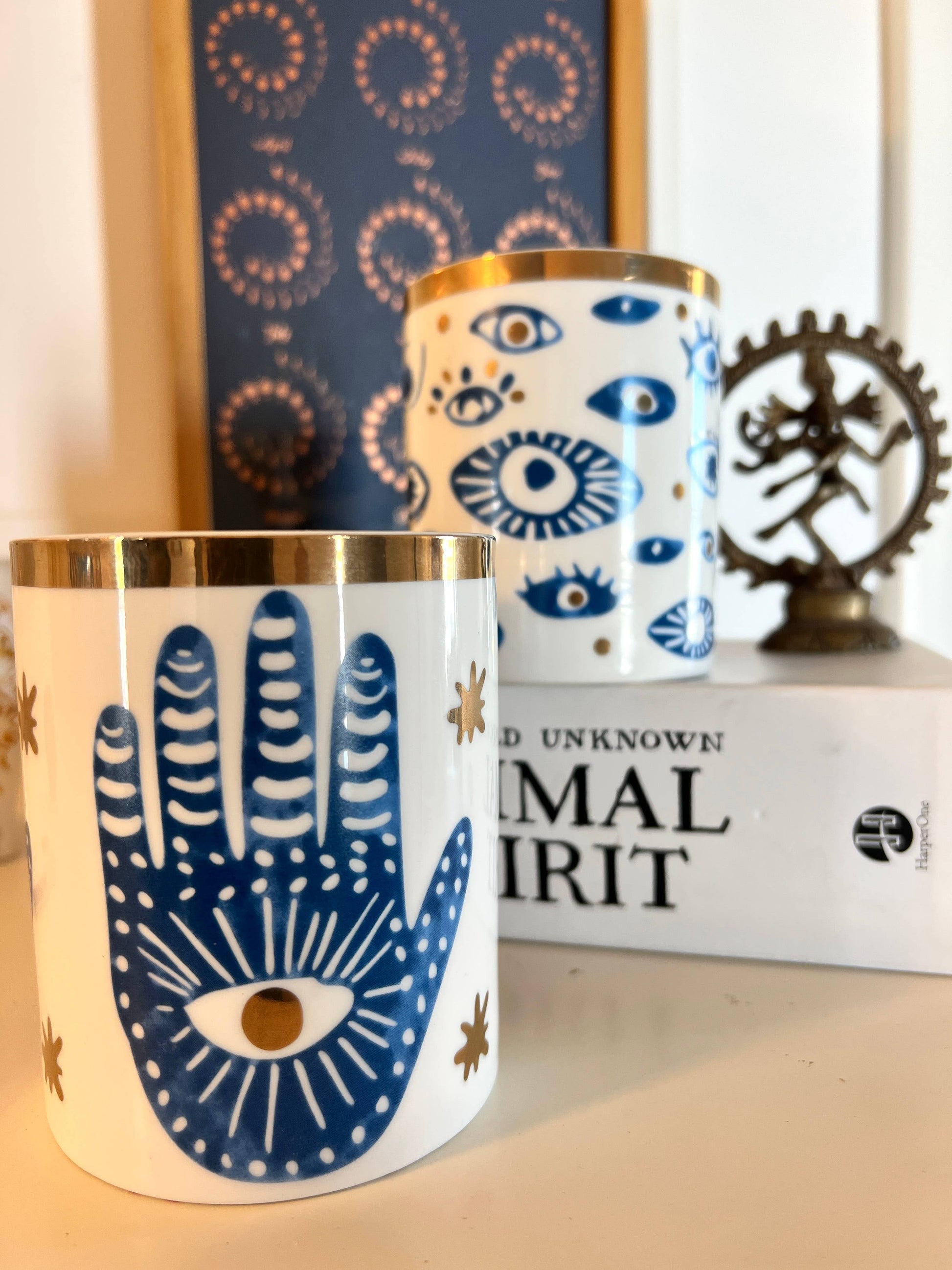 Decorative candles with eye and hand designs on a shelf.