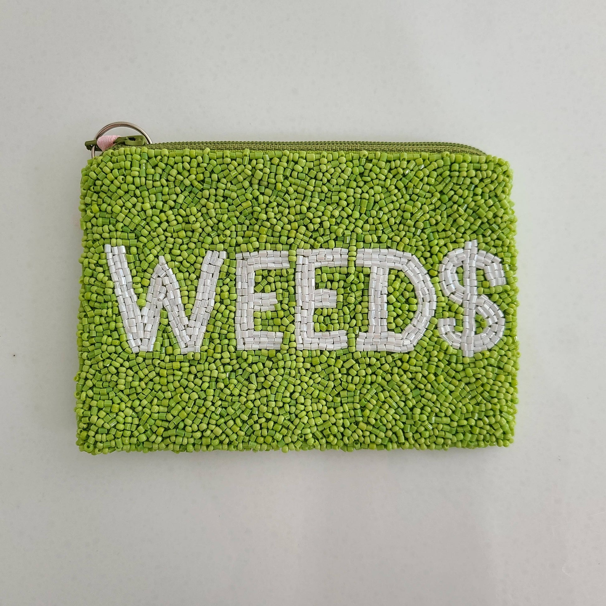 Green textured pouch with 'WEED$' text on a light gray background