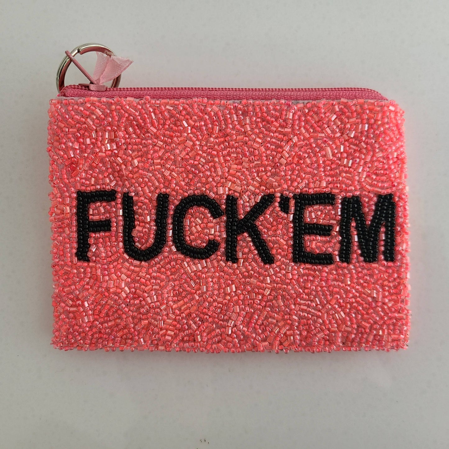 Pink beaded pouch with 'FUCK'EM' text on a gray background