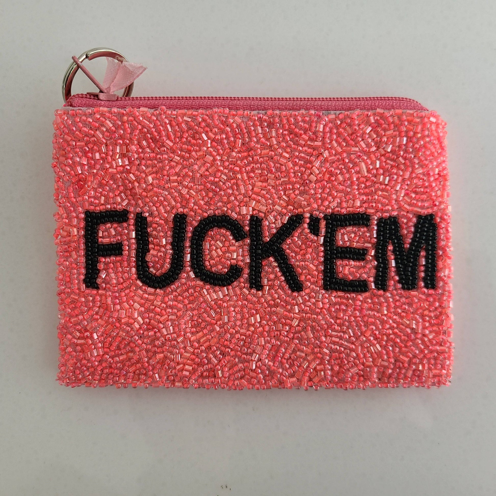Pink beaded pouch with 'FUCK'EM' text on a gray background